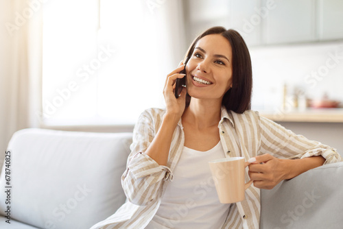 Pleasant Call. Happy Woman Talking On Phone And Drinking Coffee At Home