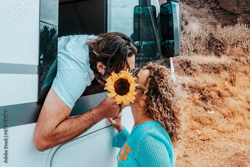 Couple of traveler kiss and love at destination. Man inside camper van and woman outside in relationship. Happiness and traveler lifestyle. Modern rv vehicle for road trip holiday vacation. Off grid