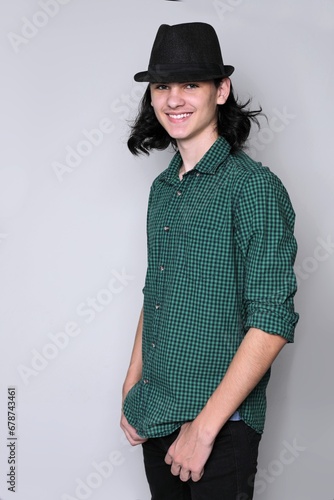 Fashion young guy in slapper with long hair, smiling, studio, standing pose photo