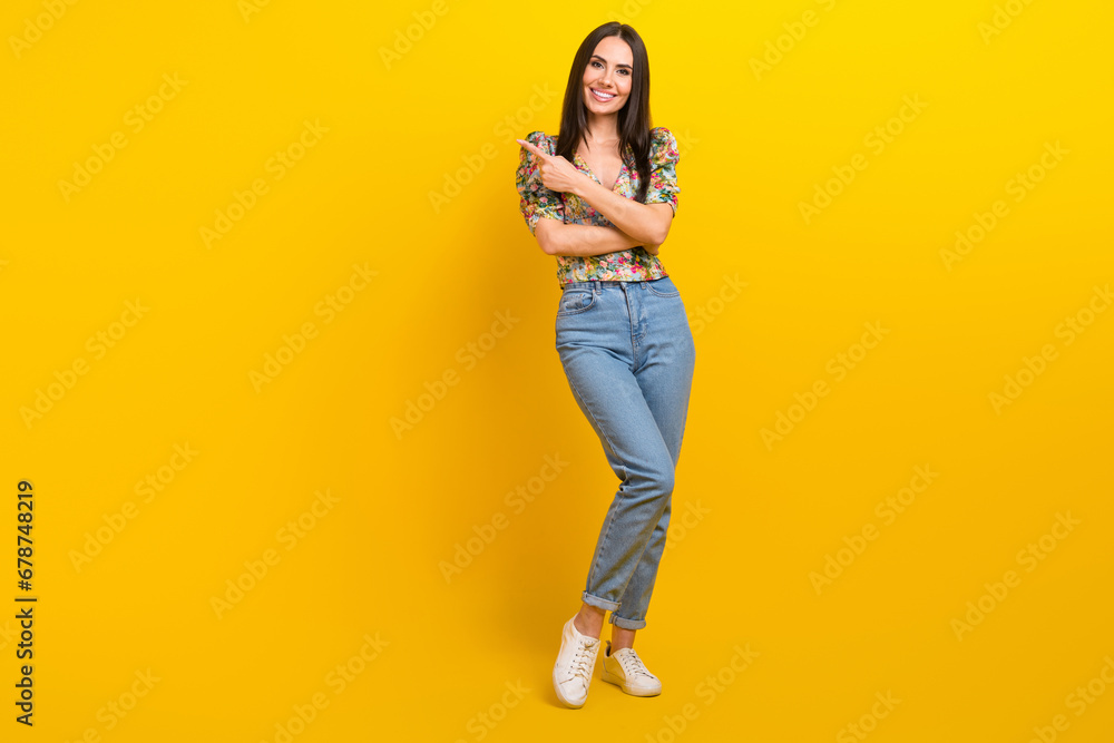 Full length photo of optimistic cute dressed flower print blouse indicating at offer empty space isolated on yellow color background Full length photo of optimistic cute dressed flower print blouse indicating at offer empty space isolated on yellow color background