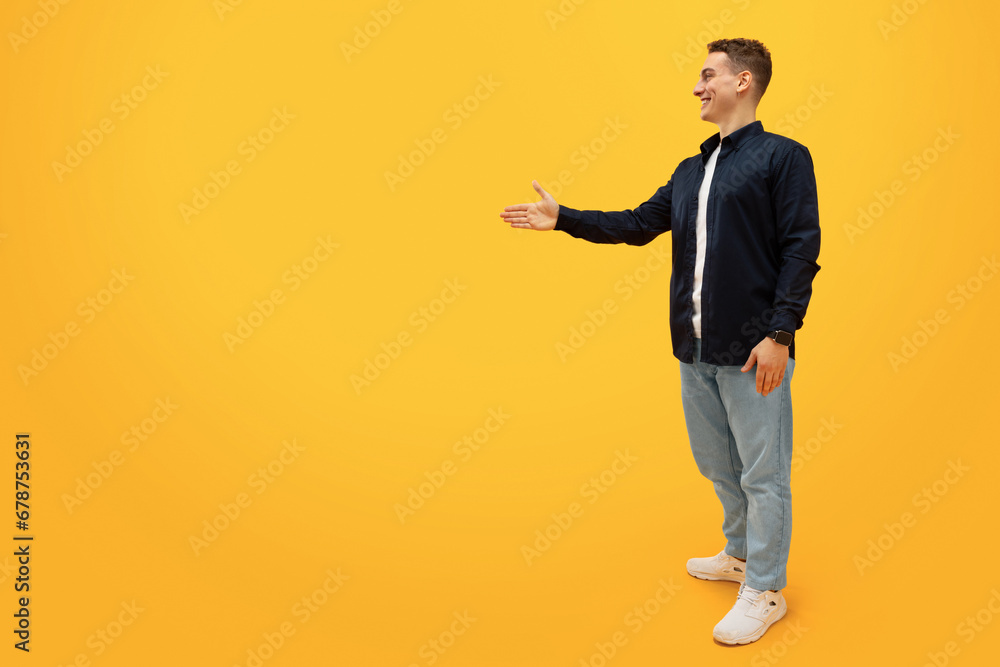 Young man 20s standing with outstretched hand for greeting Young man 20s standing with outstretched hand for greeting