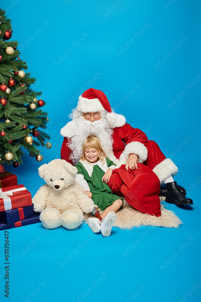 happy girl with prosthetic leg and teddy bear and sitting with Santa Claus next to Christmas tree happy girl with prosthetic leg and teddy bear and sitting with Santa Claus next to Christmas tree
