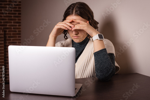 stressed woman covers head with hands, thinking about problems, working online on laptop at home