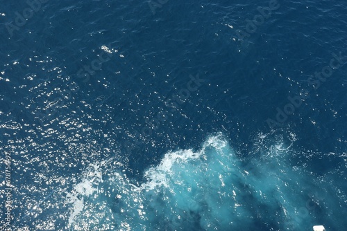 High angle of the blue sea with small waves illuminated by sun rays in the daytime