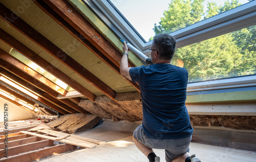 Craftsman caulking a new window in the attic. photo