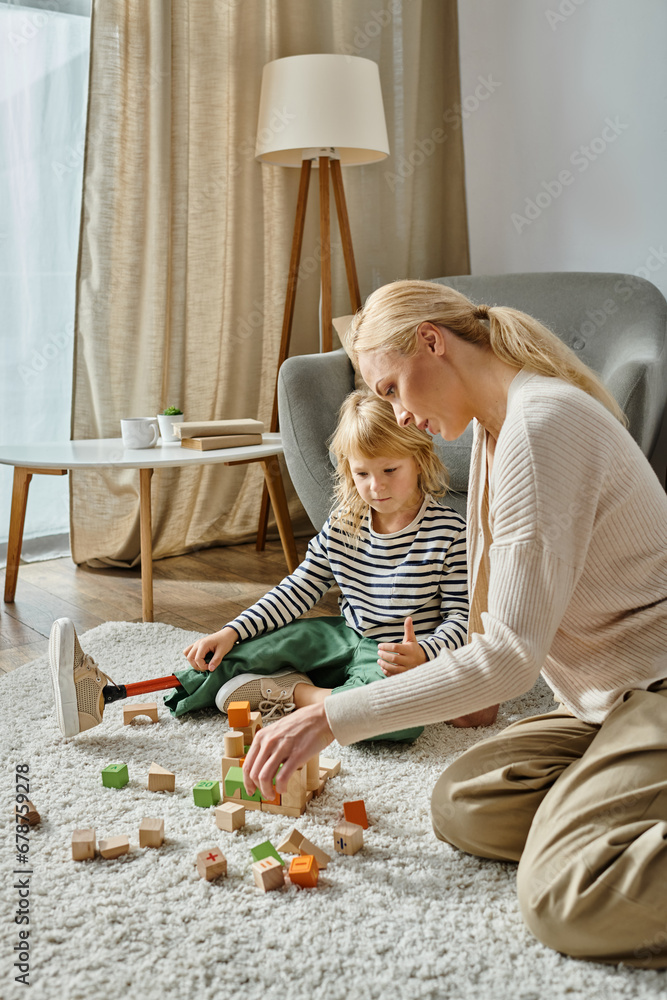 disabled girl with prosthetic leg sitting on carpet and playing with wooden toys near blonde mother disabled girl with prosthetic leg sitting on carpet and playing with wooden toys near blonde mother