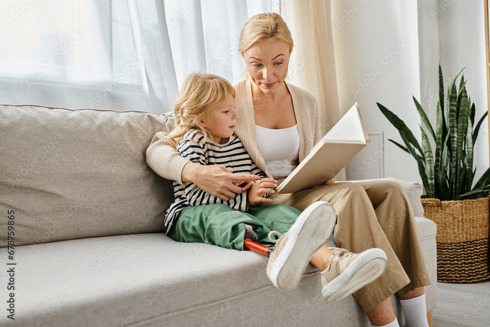 blonde woman reading book to daughter with prosthetic leg while sitting together in living room blonde woman reading book to daughter with prosthetic leg while sitting together in living room