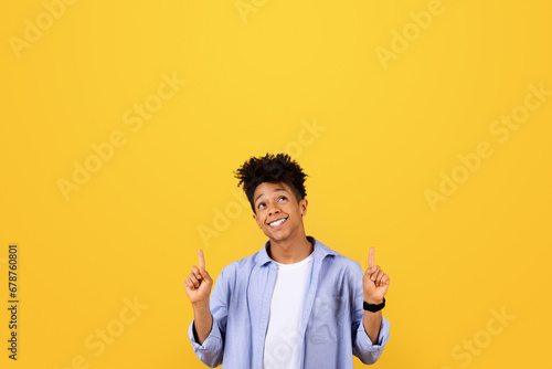 Happy black man points up at free space with both hands photo