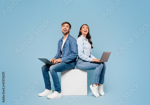 Couple with laptops look at free space on blue background photo