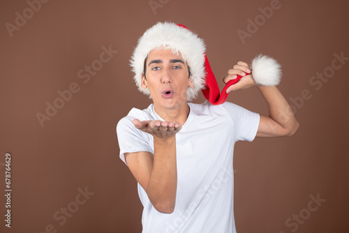 Winter. Christmas is the time of gifts. Funny attractive guy posing on a brown background. #678764629