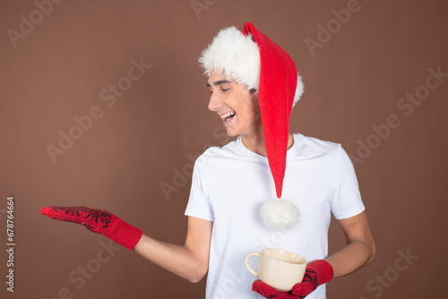 Winter. Christmas is the time of gifts. Funny attractive guy posing on a brown background. #678764664