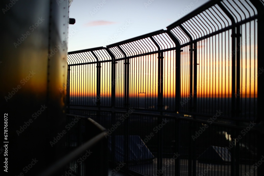 Fototapeta premium Sunset view from behind metal fence in a tower