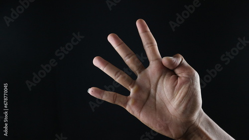Male hand gesture number four closeup isolated on a black background photo