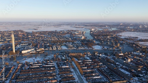 Aerial shot of a city with a river and snowy fields, on a winter day