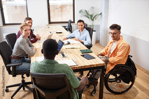 Group of young business people sitting at meeting in office and discussing working moments