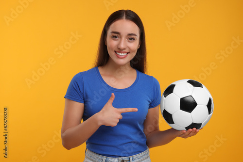Happy fan showing soccer ball on yellow background © New Africa