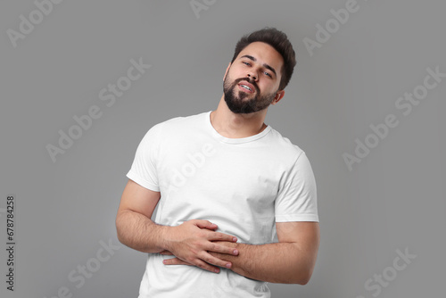 Young man suffering from stomach pain on light grey background photo
