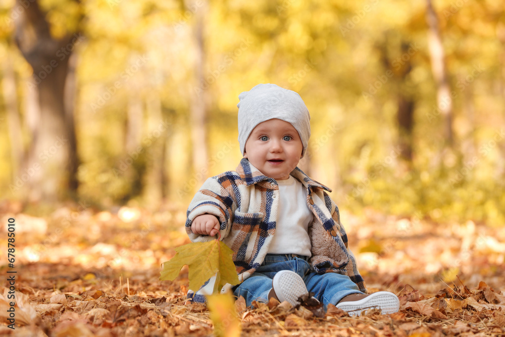 Cute little child on ground with dry leaves in autumn park, space for text Cute little child on ground with dry leaves in autumn park, space for text