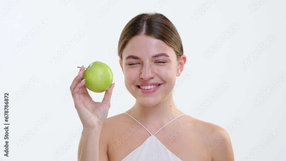 Woman takes a playful bite into a crisp green apple, carefree spirit evident in the moment. Against the white backdrop, enjoyment of the fruit capture the essence of simple pleasures. Woman takes a playful bite into a crisp green apple, carefree spirit evident in the moment. Against the white backdrop, enjoyment of the fruit capture the essence of simple pleasures.