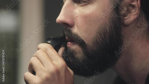 Cinematic shot of brutal bearded man shaves his beard, morning tradition, self-care. Barbershop and cosmetology. Close-up portrait, facial features and handsome man photo
