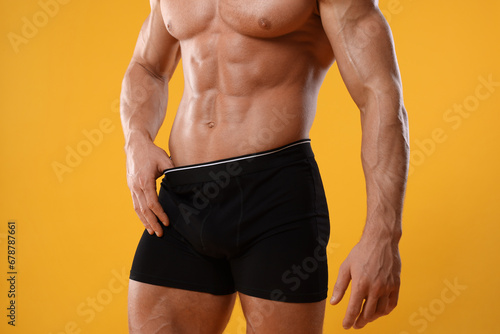 Young man is stylish black underwear on orange background, closeup