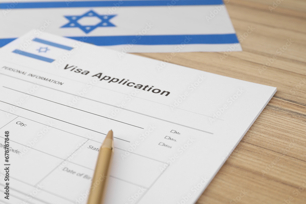 Immigration to Israel. Visa application form, pencil and flag on wooden table, closeup Immigration to Israel. Visa application form, pencil and flag on wooden table, closeup