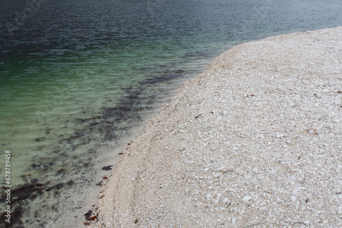 The shore of a lake with a pebble and sand.
