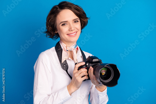 Photo of charming positive girl toothy smile arms hold camera tied on neck scarf isolated on blue color background
