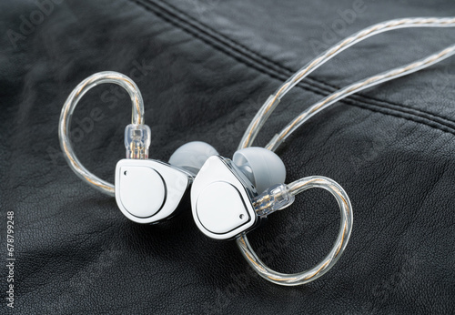 In ear monitor on a tablature background. Custom in-ear monitors with black plates. Custom in ear monitors or IEMs ready for a musician to wear on stage at a concert.	
 photo