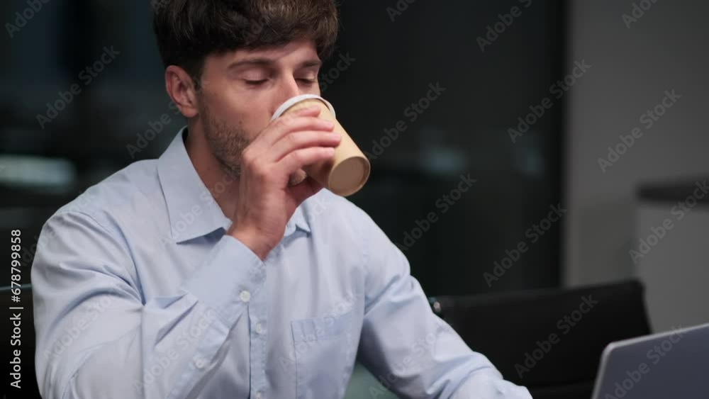 Man pauses to take a sip of hot beverage, finding brief respite amidst the tasks on laptop. The steam rises from cup, momentarily veiling focused expression. Man pauses to take a sip of hot beverage, finding brief respite amidst the tasks on laptop. The steam rises from cup, momentarily veiling focused expression.