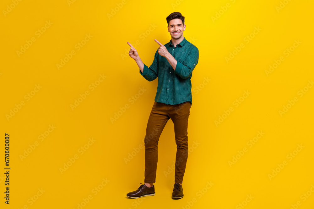 Fototapeta premium Photo of positive attractive man dressed green stylish clothes presenting novelty empty space isolated on yellow color background