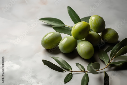 Green olives with leaves on soft grey background with copy space