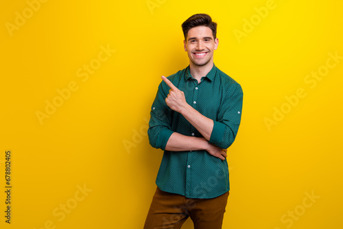 Photo of nice cheerful man dressed trendy clothes recommend product special sale banner empty space isolated on yellow color background photo