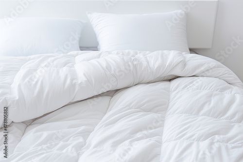 White folded duvet lying on white bed background. Preparing for household, domestic activities, hotel or home textile, white bright light and room.  © Robert
