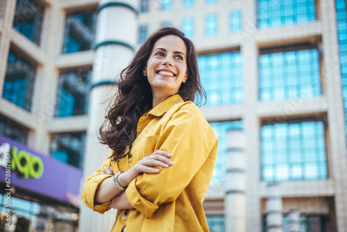 Portrait of a beautiful happy woman outdoors. Smiling woman in the city. Candid portrait of a cheerful young woman wearing an yellow shirt spending time in the city.