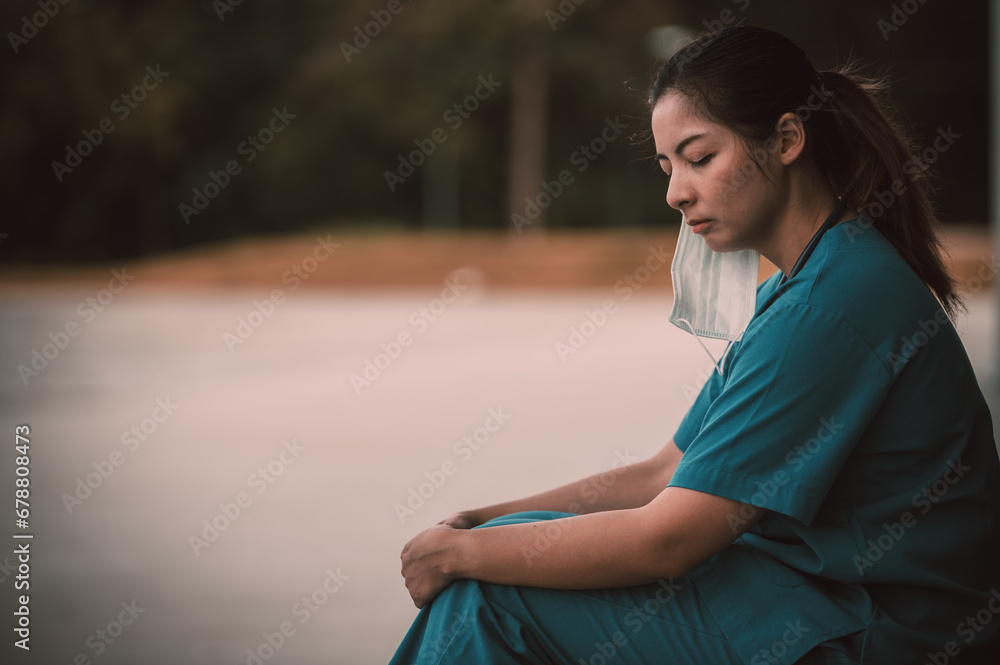 Tired depressed female asian scrub nurse wears face mask blue uniform sits on hospital floor,Young woman doctor stressed from hard work