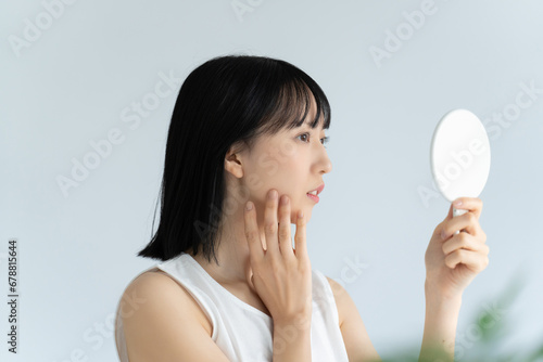 Foto 鏡で肌をチェックする白い服の若い女性