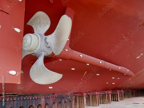 ship in dry-dock, bronze propeller and rudder on red hull	
