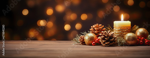 vela junto a decoración navideña de bolas, acebo y piñas, sobre soporte de madera y fondo dorado desenfocado photo