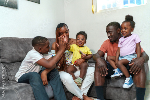 Joyful African family with kids smiling and bonding on couch in a cozy living room setting.
