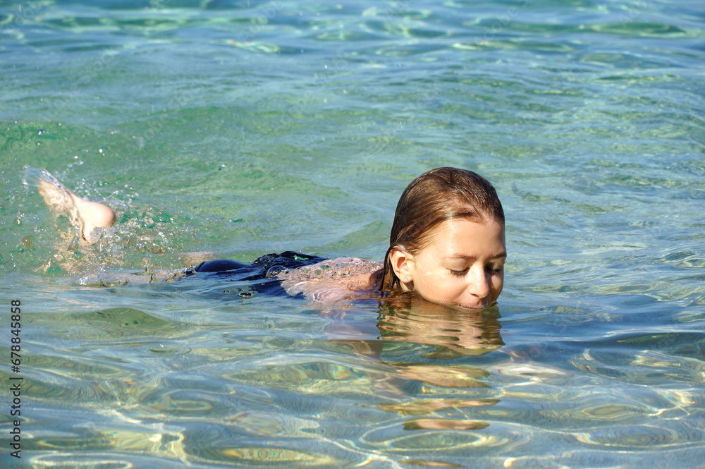 Summer joys and a little girl playing in the shallow and clear sea