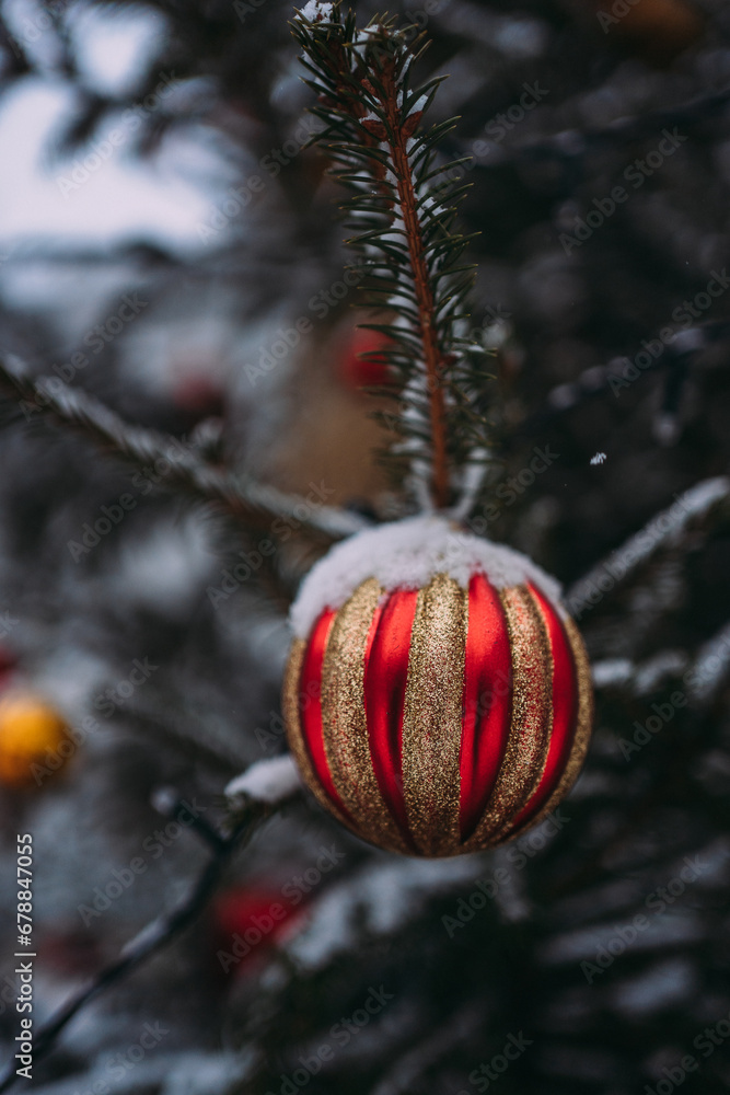 Obraz premium Snow-covered Christmas trees with red balloons and garlands on the city street. Decoration of the city for the New Year. Snow-covered New Year's streets of the city