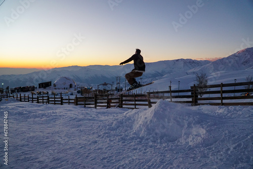 Fotografie Silhouette of a man jumping mid-air while skiing down a slope in a beautiful sun
