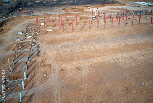 Panoramic view of the construction site with piles, pile foundations and reinforced concrete columns. In the background, excavators are removing soil and loading it into trucks. Shot from a drone. photo
