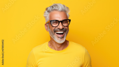 Beautiful and happy blond hair senior man looking at camera isolated on yellow background photo