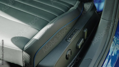 close-up of black perforated leather driver's seat with blue stitching and power adjustment. seat memory buttons and levers
