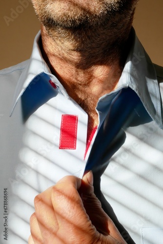 Bild auf Leinwand Male hand holding a velcro on his shirt ,unshaven face, shades from the blinds