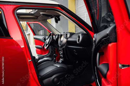 Compact, stylish and youthful crossover in bright red color. Modern black car interior.  Details interior.  © ARTUR