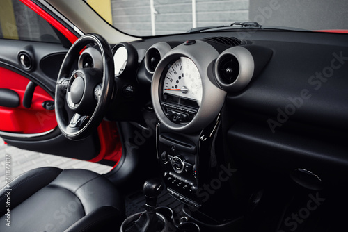 Compact, stylish and youthful crossover in bright red color. Modern black car interior.  Details interior.  © ARTUR