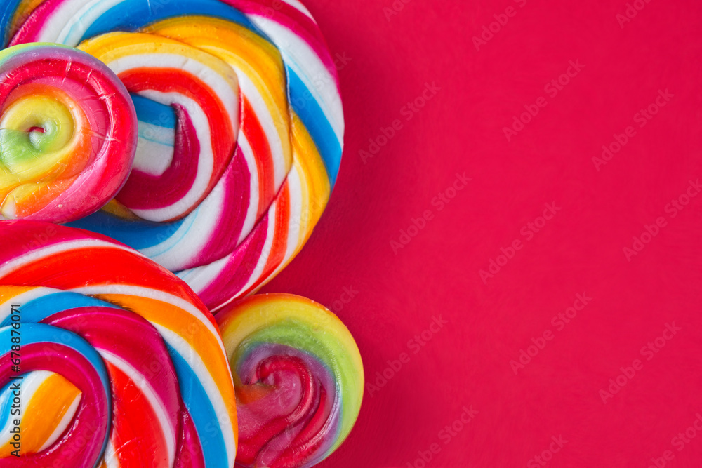 Bright and colourful candy lollipops on a red background with lots of space for text